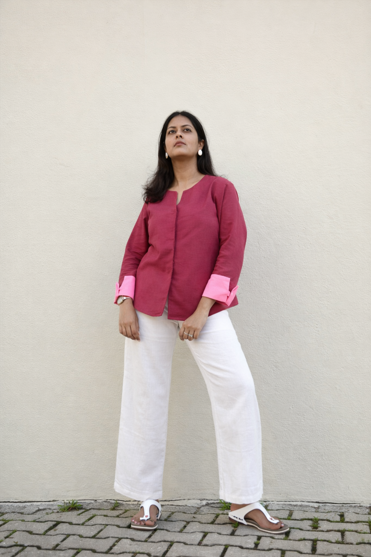 Woman wearing a pink blouse and white pants against a plain background